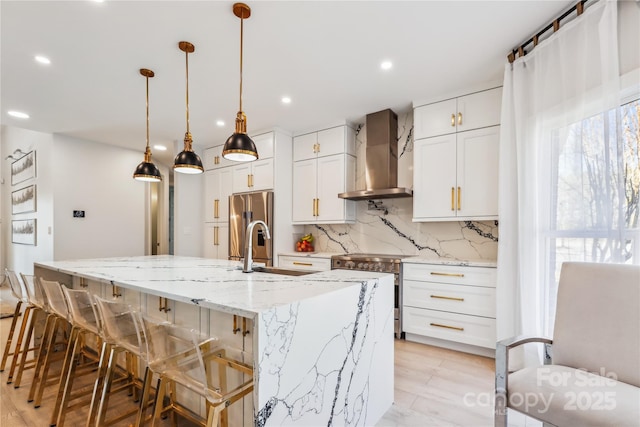 kitchen featuring hanging light fixtures, a spacious island, light stone counters, white cabinets, and wall chimney exhaust hood