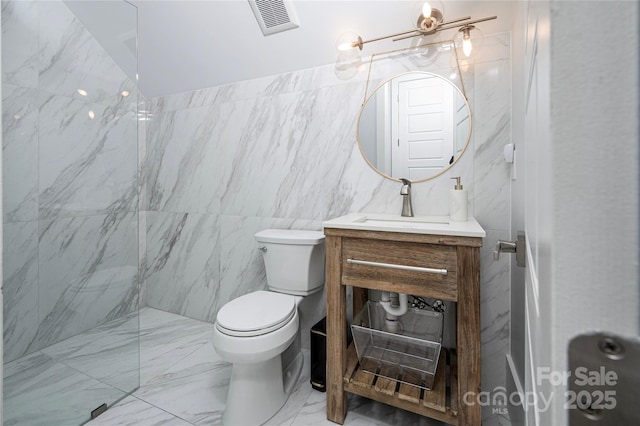 bathroom featuring vanity, a tile shower, and toilet