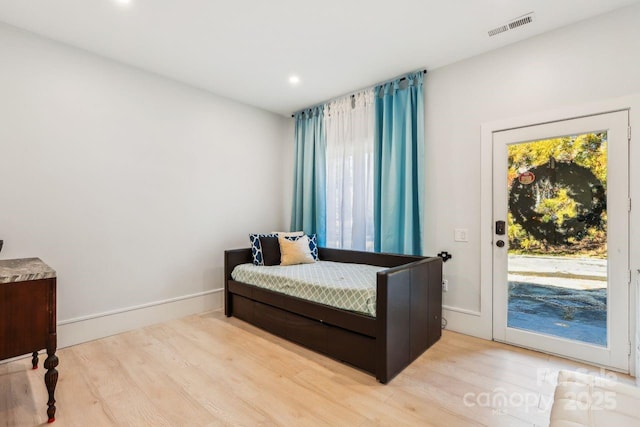 bedroom featuring multiple windows, access to outside, and light wood-type flooring