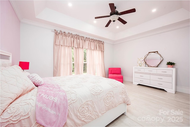 bedroom featuring light hardwood / wood-style flooring, ornamental molding, a raised ceiling, and ceiling fan