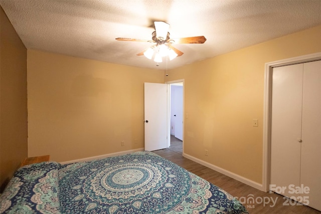 bedroom with dark hardwood / wood-style flooring, ceiling fan, and a textured ceiling