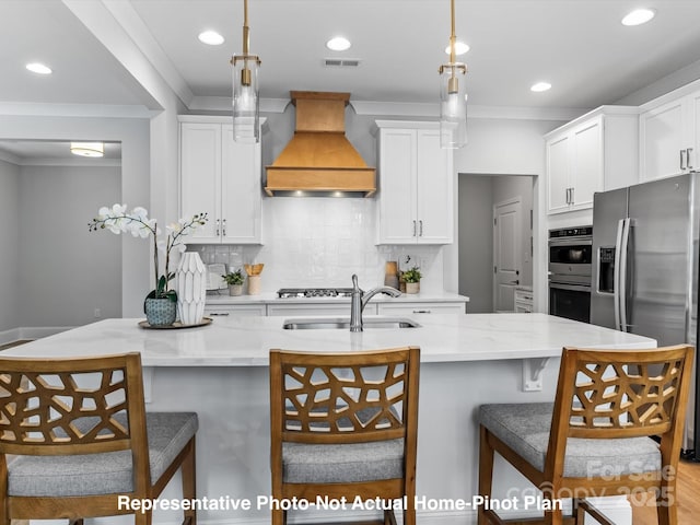 kitchen with pendant lighting, sink, a kitchen bar, stainless steel appliances, and custom range hood