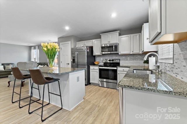 kitchen featuring sink, white cabinetry, a center island, stone counters, and stainless steel appliances