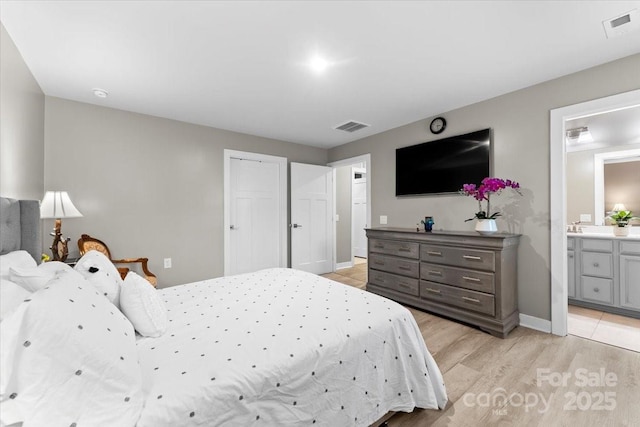 bedroom with connected bathroom and light wood-type flooring