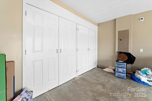 bedroom featuring concrete flooring, electric panel, and a closet