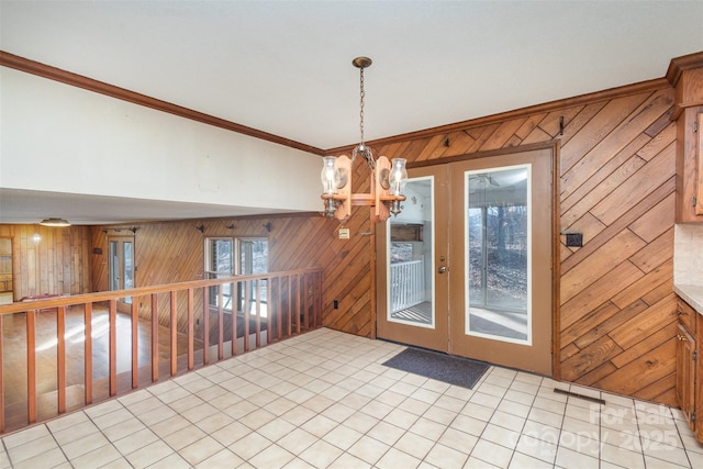 interior space featuring an inviting chandelier, ornamental molding, and wood walls