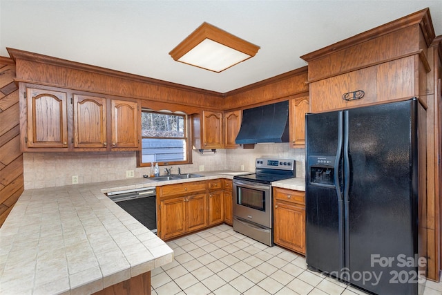 kitchen with sink, black appliances, kitchen peninsula, decorative backsplash, and wall chimney range hood