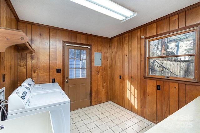 clothes washing area with wood walls, washer and clothes dryer, light tile patterned floors, and a wealth of natural light