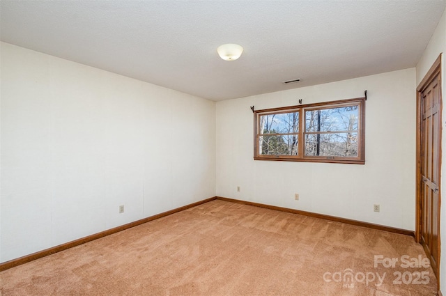 spare room with light carpet and a textured ceiling