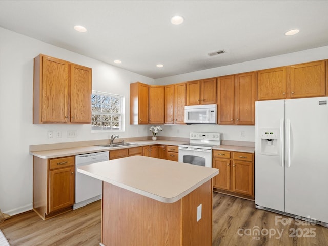 kitchen featuring a kitchen island, sink, white appliances, and light hardwood / wood-style floors