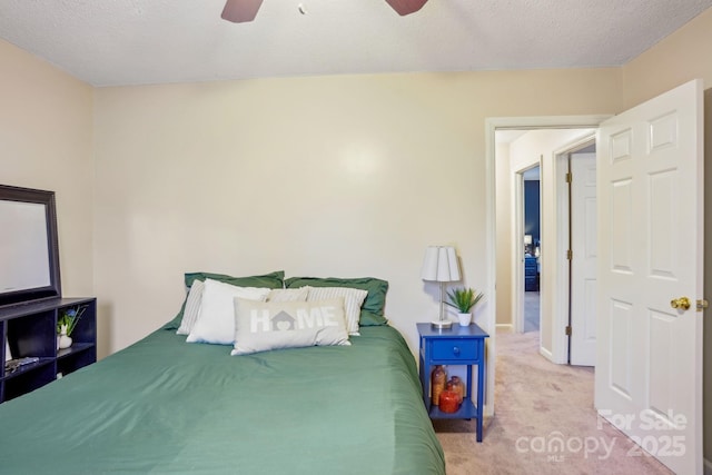 bedroom featuring ceiling fan, light colored carpet, and a textured ceiling