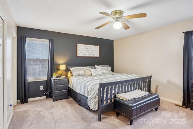 bedroom featuring ceiling fan, light colored carpet, and a textured ceiling