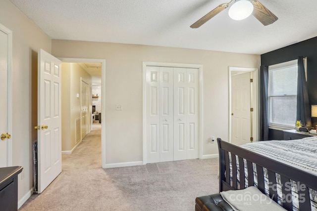 bedroom with light colored carpet, a textured ceiling, ceiling fan, and a closet