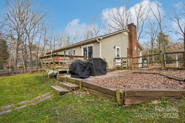 rear view of property featuring a wooden deck and a lawn