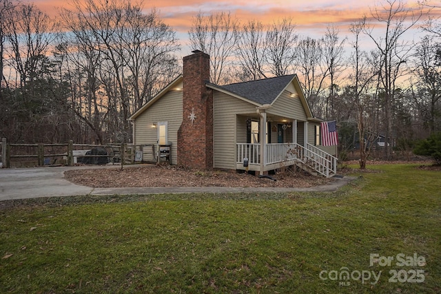 property exterior at dusk featuring covered porch and a lawn