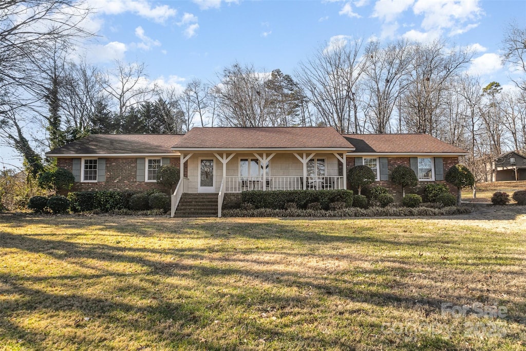 ranch-style house featuring covered porch and a front lawn