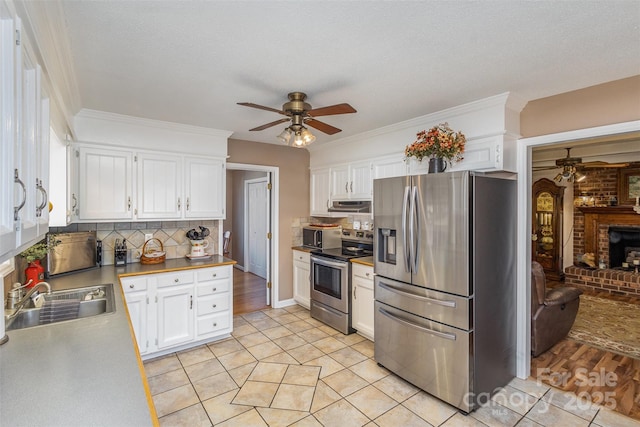 kitchen with sink, appliances with stainless steel finishes, white cabinets, ceiling fan, and backsplash