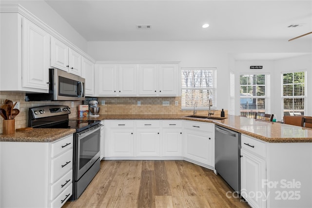 kitchen with sink, white cabinetry, stone counters, stainless steel appliances, and light hardwood / wood-style floors