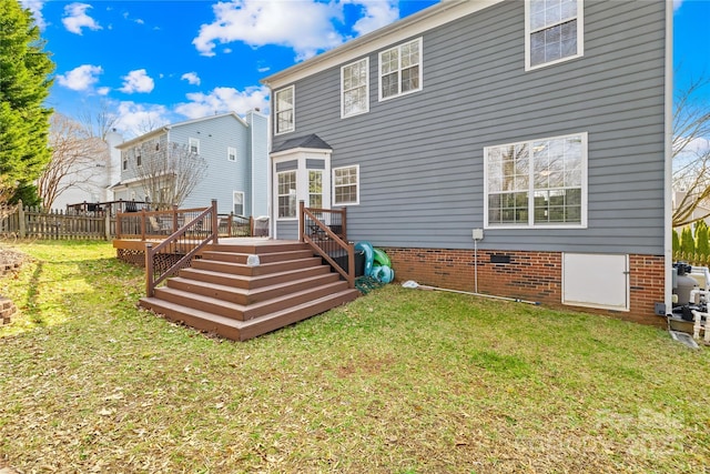 rear view of house featuring a wooden deck and a lawn