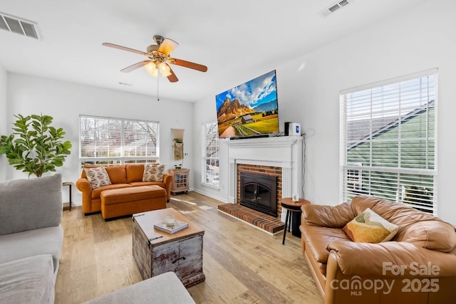 living room with ceiling fan, a fireplace, and light wood-type flooring