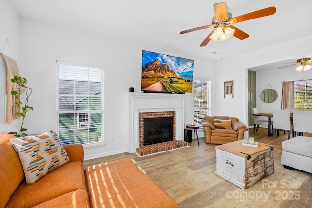 living room featuring ceiling fan, wood-type flooring, and a fireplace