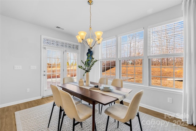 dining space with a notable chandelier, hardwood / wood-style flooring, and a healthy amount of sunlight