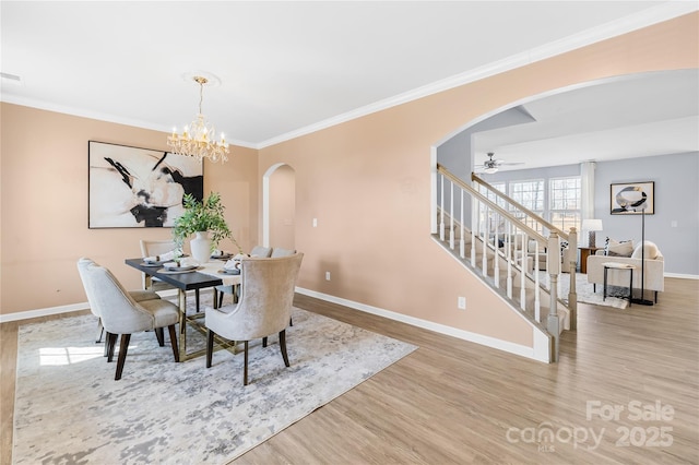 dining area featuring crown molding, light hardwood / wood-style flooring, and ceiling fan with notable chandelier