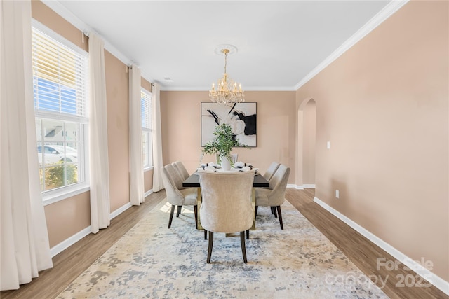 dining room with hardwood / wood-style floors, crown molding, and a notable chandelier