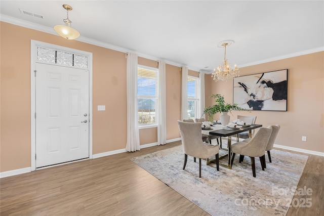 dining area with an inviting chandelier, crown molding, and light hardwood / wood-style flooring