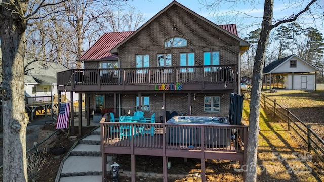 back of property with a jacuzzi, a deck, and a shed