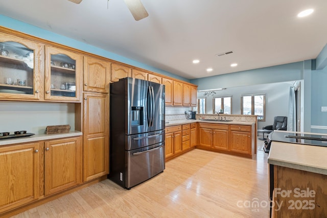 kitchen featuring stainless steel fridge with ice dispenser, sink, backsplash, kitchen peninsula, and light hardwood / wood-style flooring