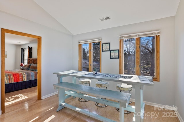 dining area with light hardwood / wood-style floors and vaulted ceiling