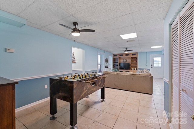 rec room featuring a paneled ceiling, light tile patterned floors, ceiling fan, and built in shelves