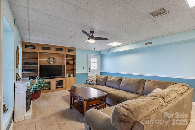 tiled living room with ceiling fan and a drop ceiling