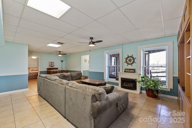 living room featuring light tile patterned flooring, ceiling fan, and a drop ceiling