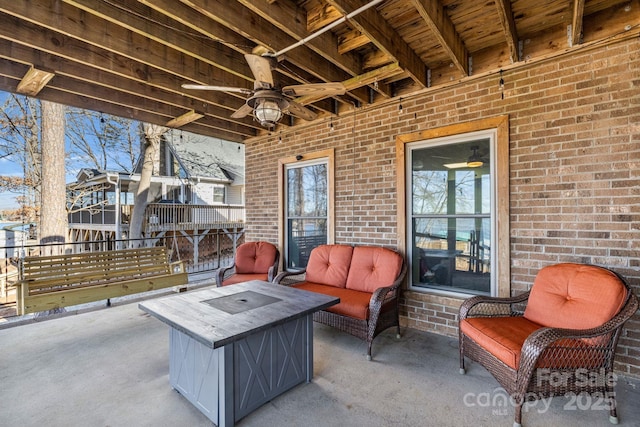 view of patio / terrace featuring ceiling fan and an outdoor living space with a fire pit