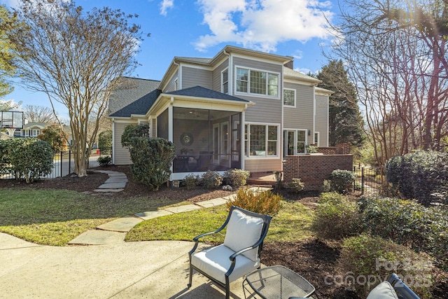 rear view of house with a patio area, a sunroom, and a lawn