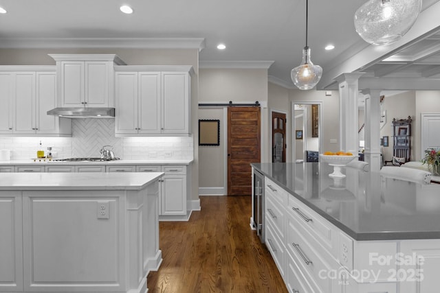 kitchen with stainless steel gas cooktop, white cabinetry, a center island, hanging light fixtures, and a barn door