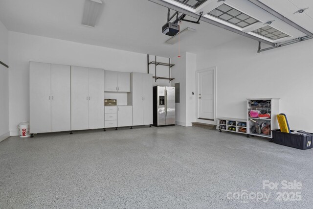 garage with a garage door opener and stainless steel fridge