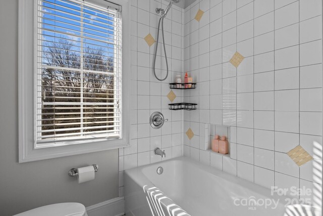 bathroom featuring tiled shower / bath, a healthy amount of sunlight, and toilet