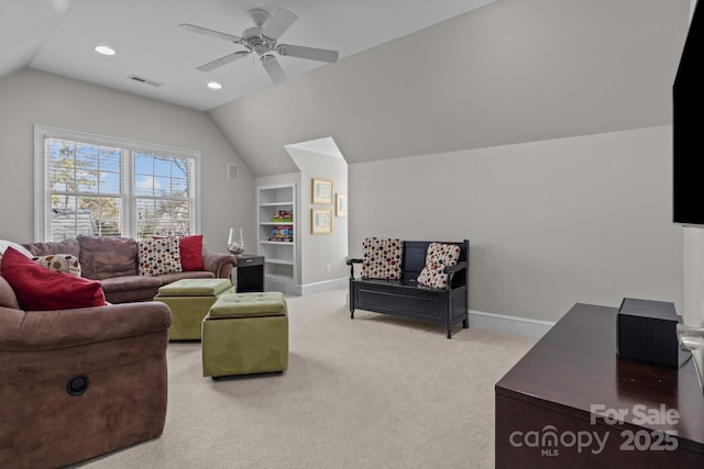 living room with built in shelves, ceiling fan, vaulted ceiling, and light carpet