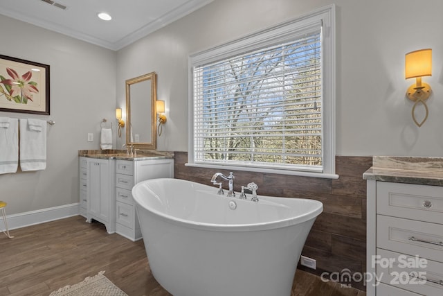 bathroom featuring a tub to relax in, wood-type flooring, tile walls, ornamental molding, and vanity