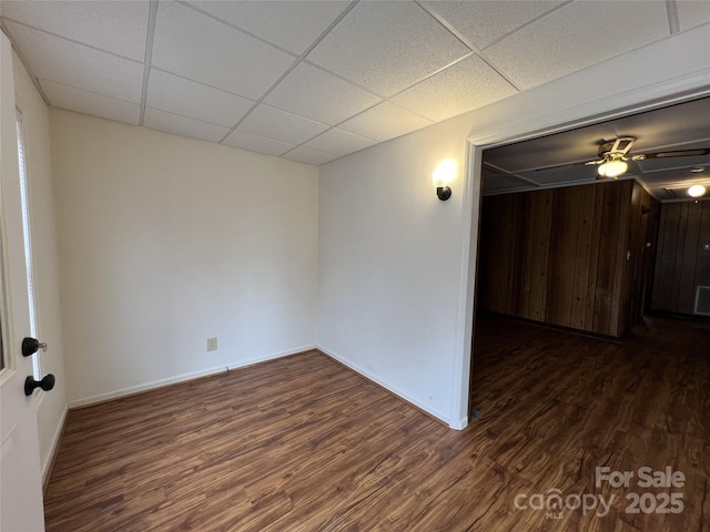 empty room with dark hardwood / wood-style flooring and a paneled ceiling