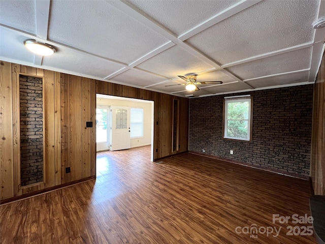 empty room featuring coffered ceiling, ceiling fan, wood-type flooring, and a healthy amount of sunlight