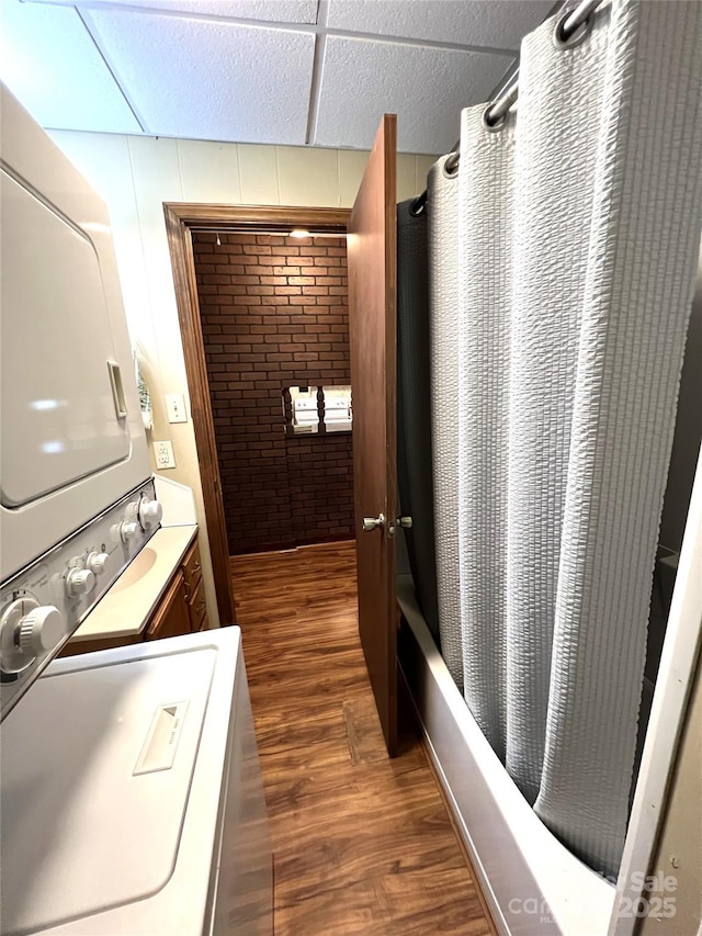 bathroom with shower / bathtub combination with curtain, hardwood / wood-style floors, vanity, and stacked washer and clothes dryer