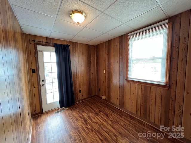 empty room featuring a healthy amount of sunlight, wooden walls, and hardwood / wood-style floors