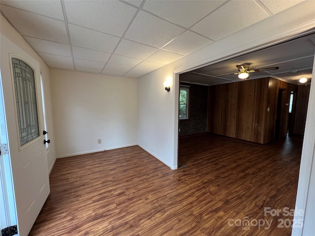 empty room featuring ceiling fan, dark hardwood / wood-style floors, and a drop ceiling