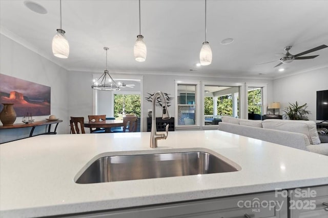 kitchen featuring pendant lighting, sink, ornamental molding, and a healthy amount of sunlight