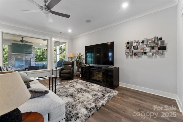 living room with crown molding, ceiling fan, wood-type flooring, and a fireplace