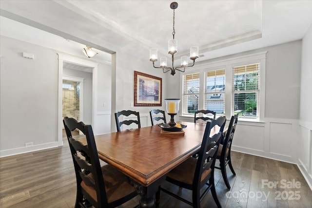 dining room with a raised ceiling, an inviting chandelier, and dark hardwood / wood-style flooring